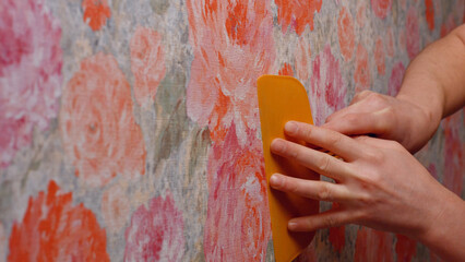 Pasting wallpaper in the house. The builder smooths the wallpaper with a spatula.