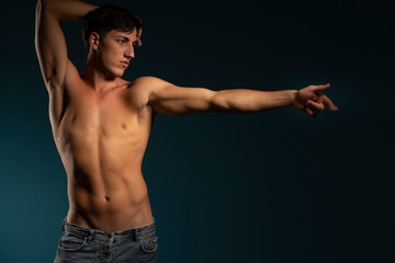 young athletic guy posing with uotstretched hand. concept: the male body after exercise and diet. men's health. Blue stdio background