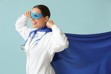 Beautiful female doctor in superhero costume showing muscles on blue background © Pixel-Shot