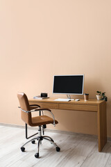 Stylish workplace with modern computer and comfortable armchair near color wall