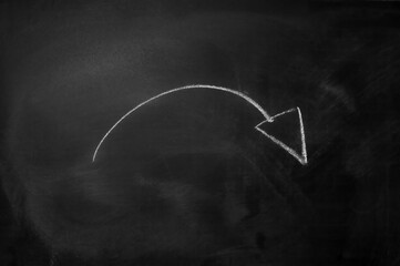 Curved arrow drawn with white chalk on a black blackboard