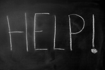 Word "help" with an exclamation written with white chalk on a black blackboard Word "help" with an exclamation written with white chalk on a black blackboard