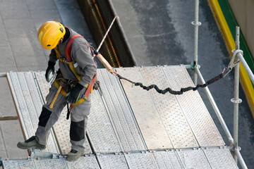 construction workers with safety equipment assembling scaffolding for maintenance of building...