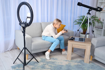 Teenage blogger with game pad recording video at home