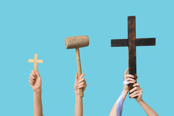 Female hands with wooden crosses and mallet on color background. Good Friday concept