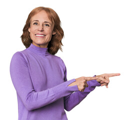 Redhead mid-aged Caucasian woman in studio excited pointing with forefingers away.