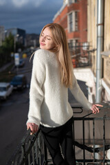 Young attractive blonde woman standing on the balcony	
