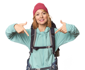 Middle-aged Caucasian woman with hiking gear points down with fingers, positive feeling.