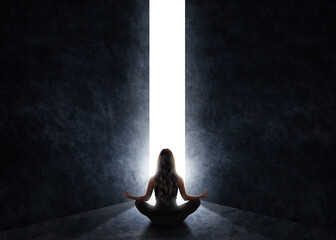 Woman in meditation position while a door opens and light enters