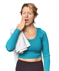 Caucasian woman in sportswear with towel yawning showing a tired gesture covering mouth with hand.