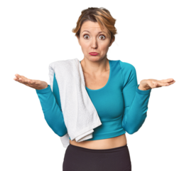 Caucasian woman in sportswear with towel doubting and shrugging shoulders in questioning gesture.