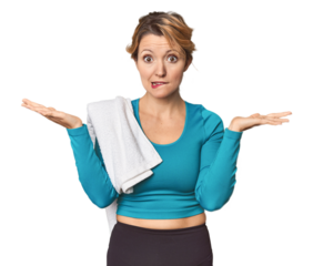 Caucasian woman in sportswear with towel confused and doubtful shrugging shoulders to hold a copy space.