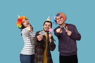 Young friends in funny disguise with whistles and paper stickers on blue background. April fool's...