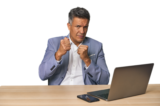 Elegant businessman at desk with laptop throwing a punch, anger, fighting due to an argument, boxing.