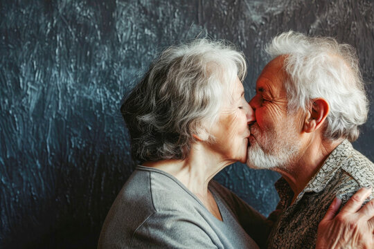portrait of beautiful happy cheerful ederly couple kissing on dark background
