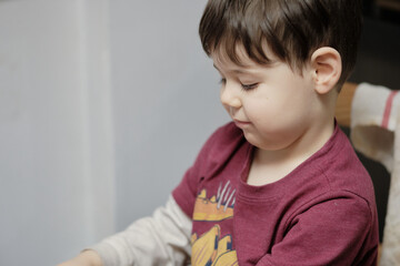curious young boy playing with a toy pizza cutter at the kitchen table