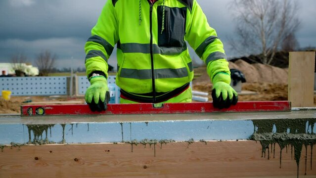 Construction Worker Using Level on Insulated Concrete Forms at Building Site