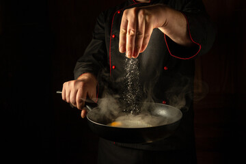 The chef adds salt to a steaming hot pan of fried eggs. Low key menu concept for a restaurant with advertising space. Grande cuisine