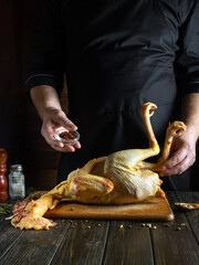 An experienced chef prepares raw rooster in a restaurant kitchen. Before roasting, the cook adds...