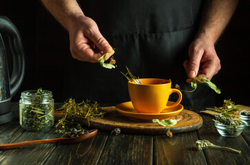 An herbalist brews tea from medicinal dry herbs. The hand holds dry medicinal linden, which can be...