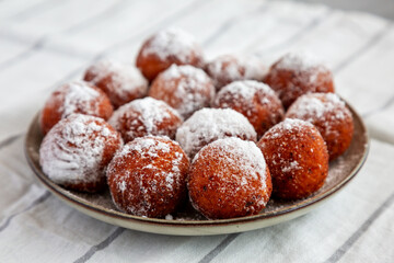 Homemade Fried Donut Holes with Powdered Sugar on a Plate, low angle view.