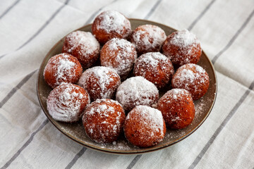 Homemade Fried Donut Holes with Powdered Sugar on a Plate, side view.