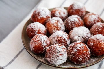 Homemade Fried Donut Holes with Powdered Sugar on a Plate, side view. Space for text.