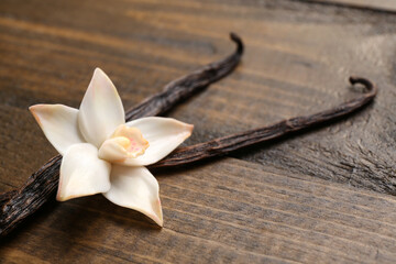 Beautiful vanilla flower and sticks on wooden background - obrazy, fototapety, plakaty