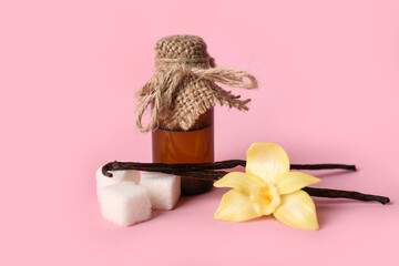 Bottle of vanilla extract, sticks and sugar on pink background