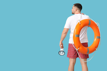 Young lifeguard with lifebuoy and megaphone on blue background