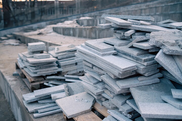 Piles of granite tiles ready for installation at a new building site at dawn.