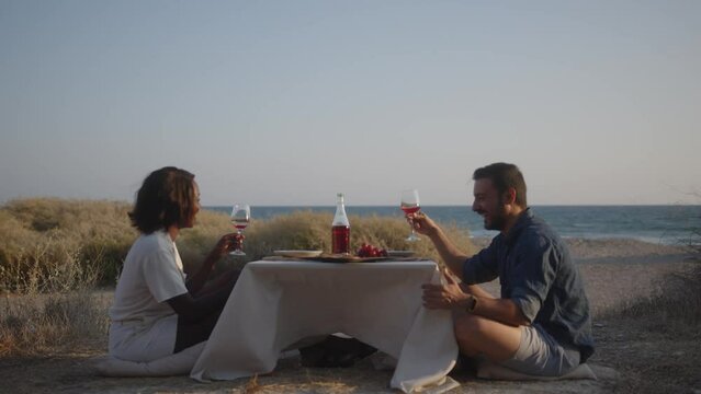 Happy multiethnic friends laughing drinking wine during summer seaside holidays