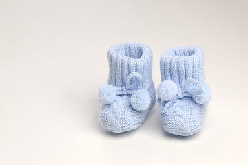 baby booties, for newborns, the first shoes with delicate feet on a light background