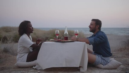 Multiethnic husband and wife having romantic dinner by the sea