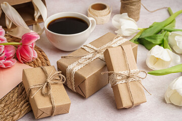 Gift boxes with beautiful tulips and cup of coffee on white background