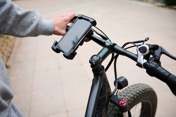 Cyclist sets up adjustments on mockup smartphone, renting electric bike using rental app. Bike...