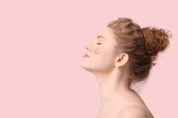 Beautiful young woman with makeup foundation on her face against pink background