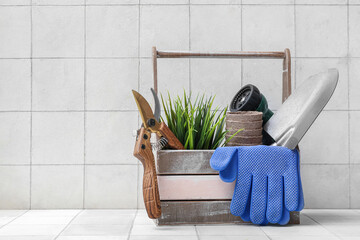 Basket with pruner, shovel and gardening gloves on table against white background