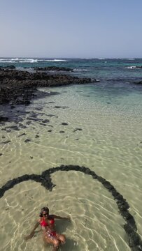 Heart-shaped stone formation in shallow beach waters at sunset
