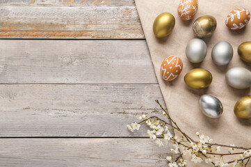 Easter eggs and blooming branches on grey wooden background. Top view