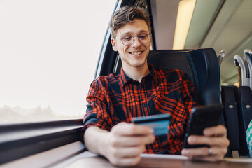 Portrait of a trendy man sitting in a train and shopping online on the phone.