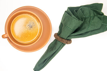 Xícara de café preto com espuma dourada, pires e xicara em terracota, bege, marrom, terra, lenço...