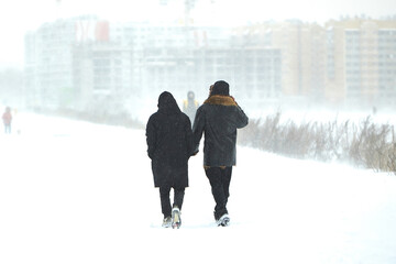 Two People Walking Down a Snow Covered Path During Winter Snowstorm