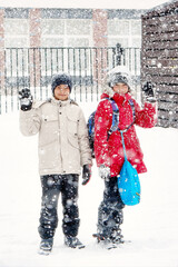 Two teenage friends stand side by side in the middle of a snowfall