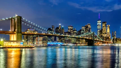  Manhattan skyline and Brooklyn Bridge illuminated at night in New York City © lucky-photo