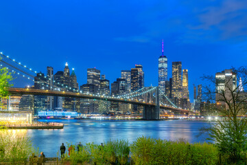 Manhattan skyline and Brooklyn Bridge illuminated at night in New York City - 770063988