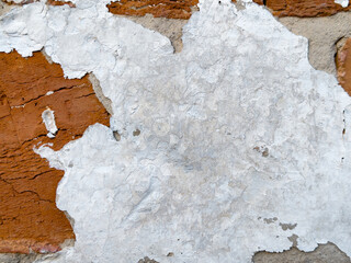 Close-up of a rough brick wall with peeling paint revealing the aged brick underneath.