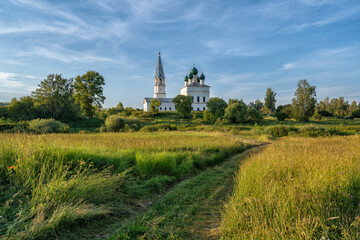 Rustic landscape, road through the field, ahead of the church in the village of Osenevo, Russia.
