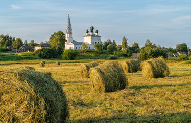 Rustic landscape, road through the field, ahead of the church in the village of Osenevo, Russia.