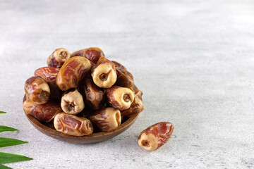 Dried fruit sagay dates in a wooden bowl on a gray background. 